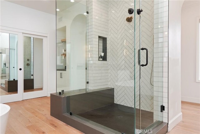 bathroom with independent shower and bath and hardwood / wood-style floors