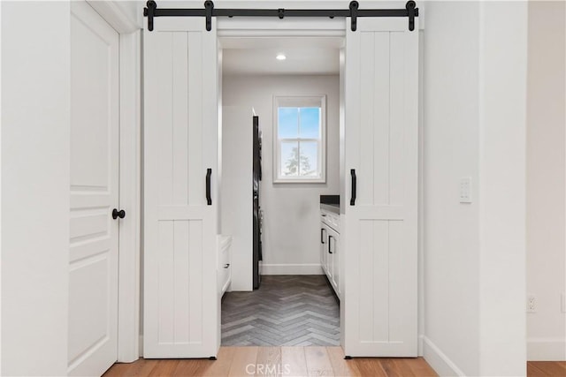 corridor featuring light parquet floors and a barn door