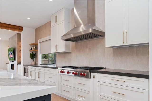 kitchen with stainless steel gas cooktop, backsplash, white cabinetry, and wall chimney range hood