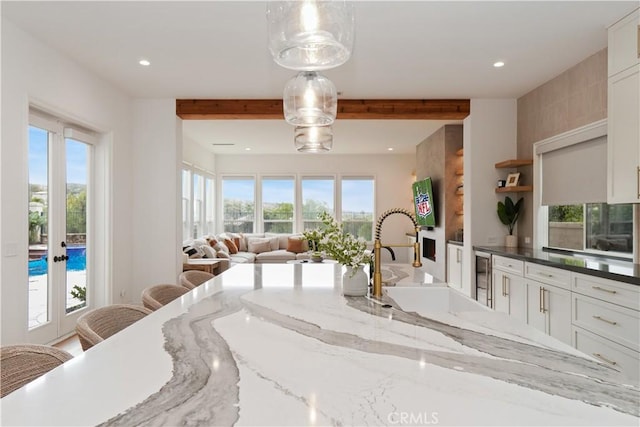 kitchen featuring pendant lighting, sink, dark stone countertops, white cabinets, and a kitchen breakfast bar