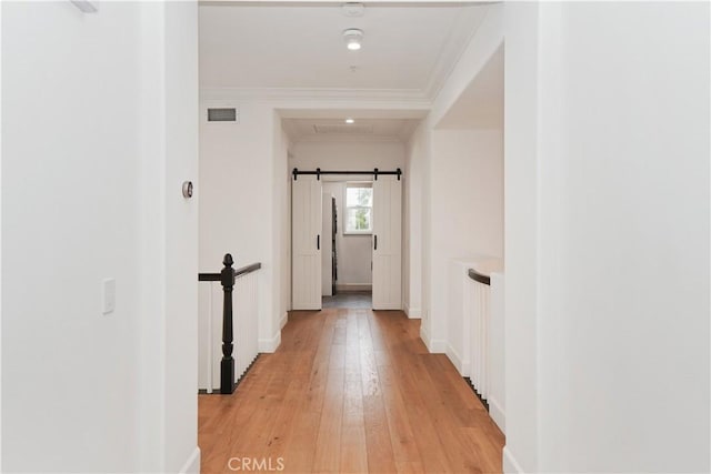 hallway with ornamental molding, a barn door, light hardwood / wood-style flooring, and radiator heating unit