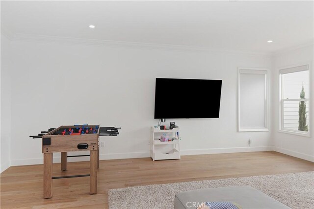 playroom featuring light wood finished floors, crown molding, and baseboards