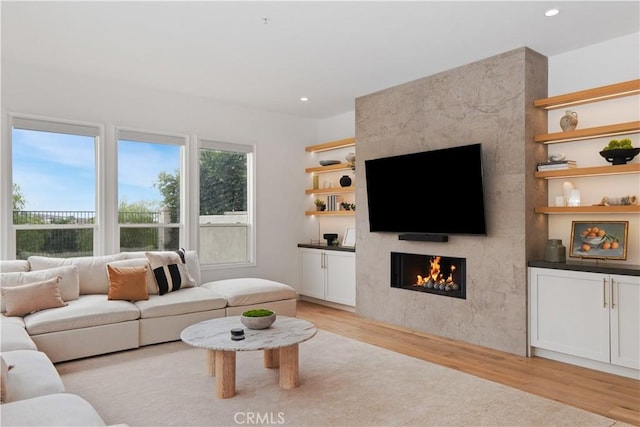 living area featuring a tiled fireplace, recessed lighting, and light wood-style flooring