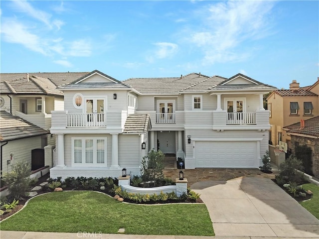 view of front of property featuring a tiled roof, french doors, driveway, a balcony, and an attached garage