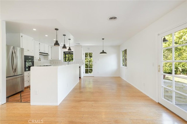 kitchen with a kitchen island, stainless steel refrigerator, white cabinetry, oven, and hanging light fixtures