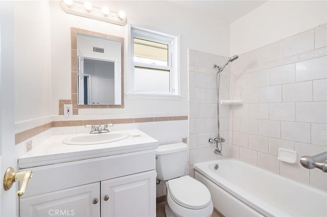 full bathroom with tiled shower / bath, vanity, and toilet