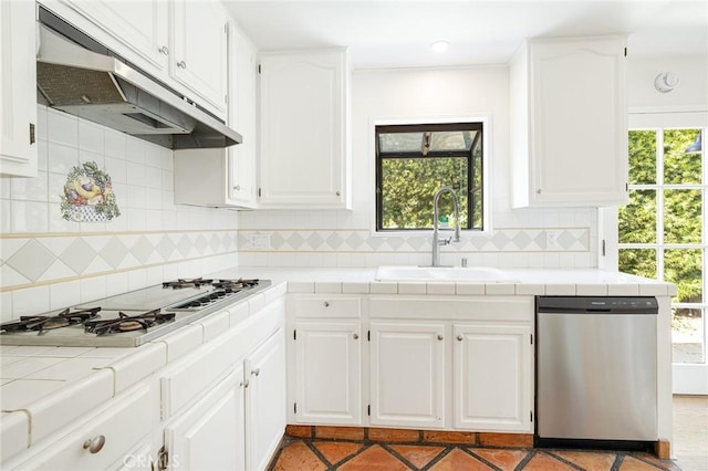 kitchen featuring stainless steel dishwasher, tile countertops, sink, and white cabinets