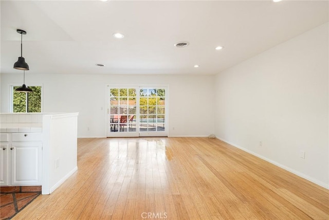 unfurnished living room featuring a wealth of natural light and light hardwood / wood-style floors