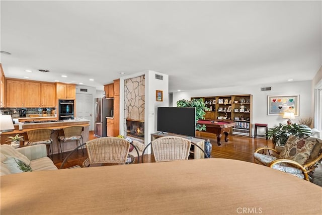 dining space featuring pool table, dark hardwood / wood-style floors, and a stone fireplace