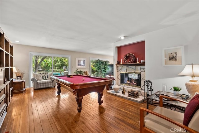 recreation room with hardwood / wood-style flooring, a stone fireplace, and billiards