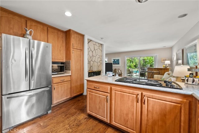 kitchen with appliances with stainless steel finishes, hardwood / wood-style floors, and backsplash