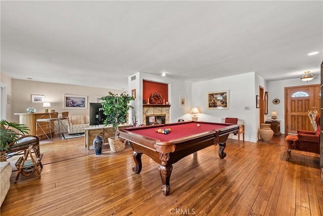 playroom featuring hardwood / wood-style flooring, a stone fireplace, and pool table