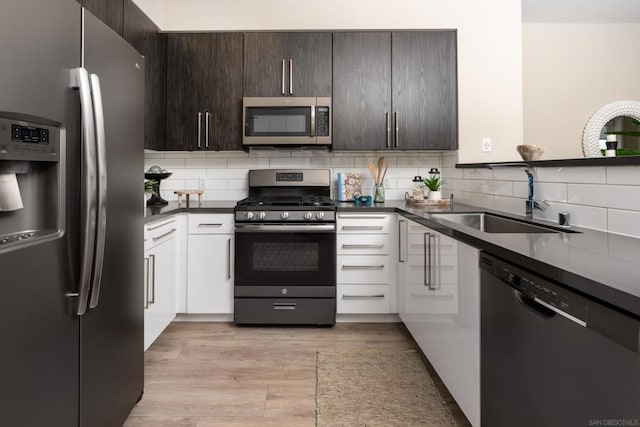 kitchen with appliances with stainless steel finishes, tasteful backsplash, sink, white cabinets, and dark brown cabinets