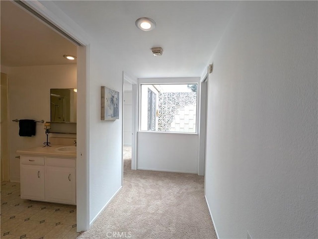 hall featuring sink and light colored carpet