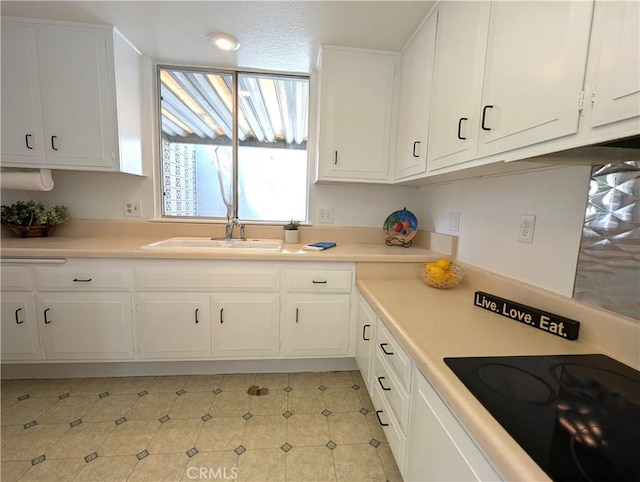 kitchen with white cabinetry, black electric stovetop, and sink