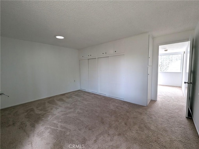 unfurnished bedroom featuring a closet, light carpet, and a textured ceiling