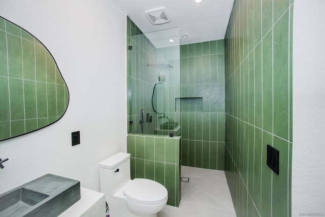 bathroom featuring tile patterned floors, toilet, and tiled shower