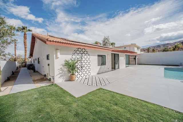 back of house with a mountain view, a lawn, and a patio