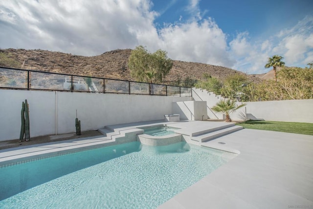 view of pool with a mountain view, a patio, and an in ground hot tub