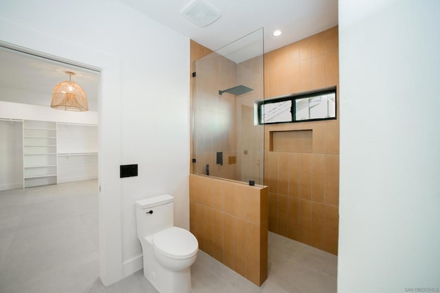 bathroom featuring tiled shower and toilet