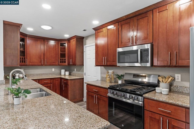 kitchen with light stone counters, sink, and appliances with stainless steel finishes