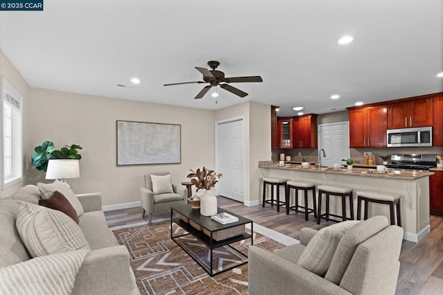 living room featuring dark hardwood / wood-style floors, sink, and ceiling fan