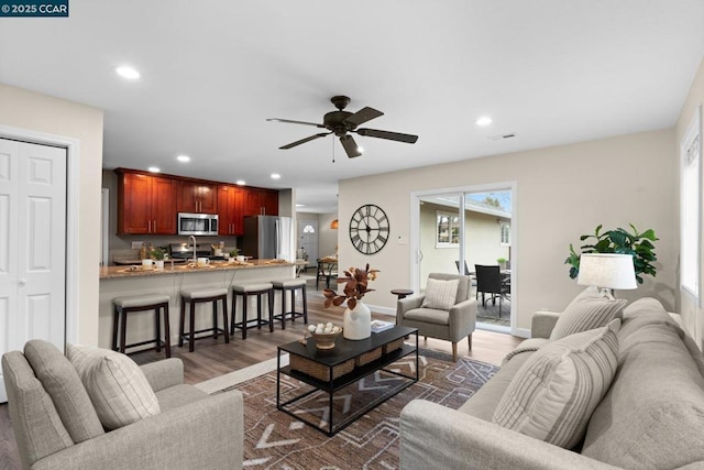 living room featuring sink, dark wood-type flooring, and ceiling fan