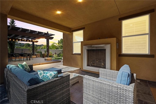 patio terrace at dusk featuring an outdoor living space with a fireplace and a pergola