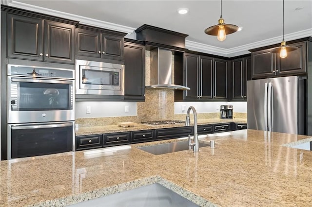 kitchen featuring wall chimney exhaust hood, light stone counters, ornamental molding, appliances with stainless steel finishes, and pendant lighting