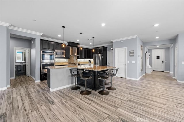 kitchen featuring a breakfast bar, light stone counters, hanging light fixtures, an island with sink, and stainless steel appliances