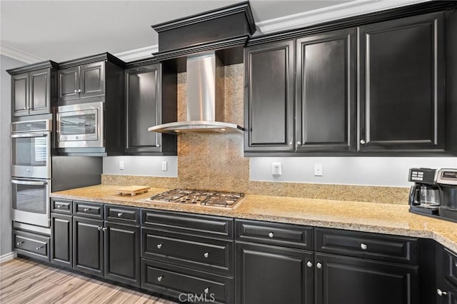 kitchen with appliances with stainless steel finishes, backsplash, ornamental molding, light hardwood / wood-style floors, and wall chimney exhaust hood