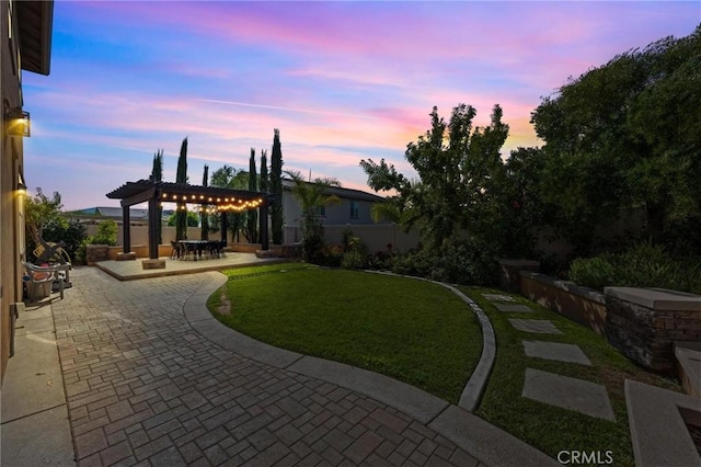 yard at dusk with a patio area and a pergola