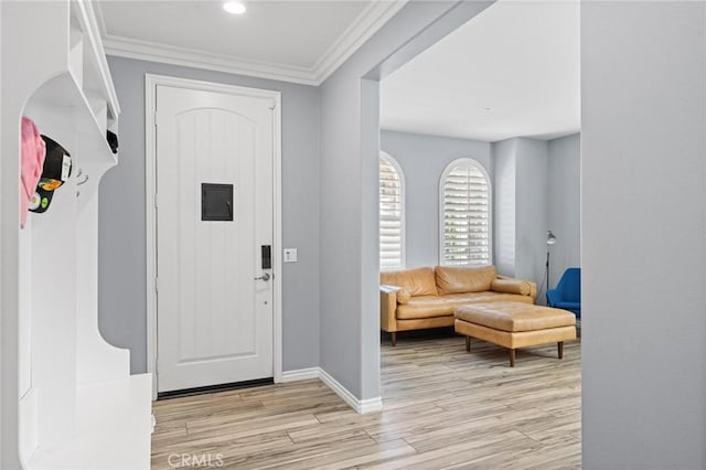 foyer entrance with ornamental molding and light wood-type flooring