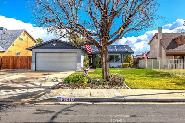 view of front of property featuring a front yard, concrete driveway, fence, and solar panels