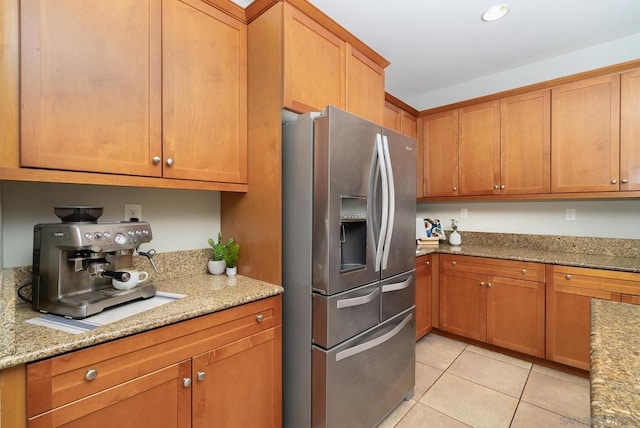 kitchen featuring stainless steel fridge, light stone countertops, and light tile patterned floors