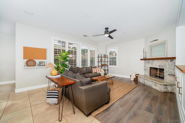 living room with a fireplace, ceiling fan, and light wood-type flooring