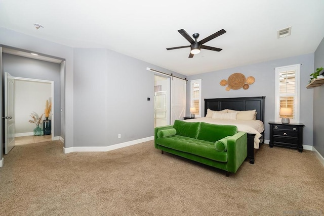 carpeted bedroom featuring a barn door and ceiling fan