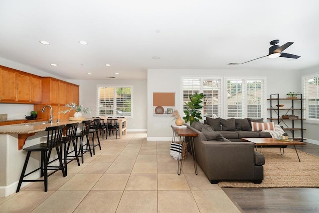 living room with sink, light tile patterned floors, a wealth of natural light, and ceiling fan