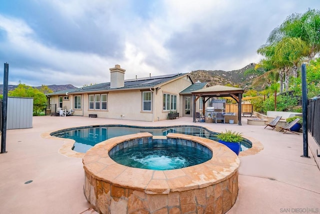 view of swimming pool featuring a mountain view, a gazebo, a patio, and an in ground hot tub