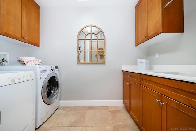 clothes washing area featuring separate washer and dryer, light tile patterned floors, sink, and cabinets