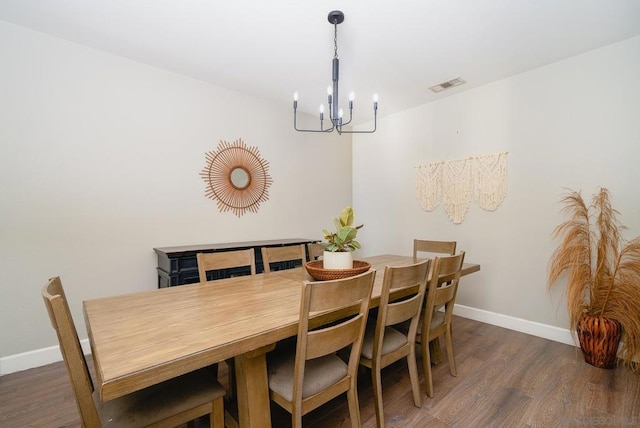 dining area with dark hardwood / wood-style floors and a notable chandelier