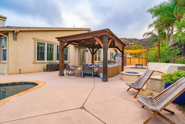 view of patio with a gazebo, a fenced in pool, a mountain view, and an outdoor living space with a fire pit