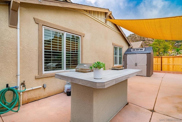 view of patio / terrace featuring a grill and a storage unit