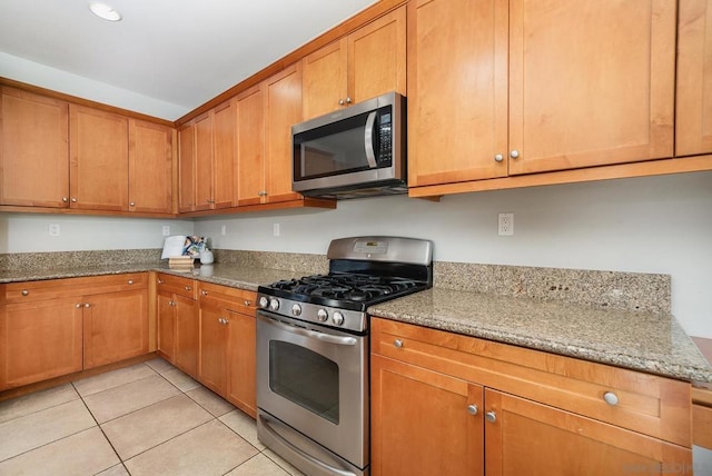 kitchen with light stone counters, light tile patterned floors, and appliances with stainless steel finishes