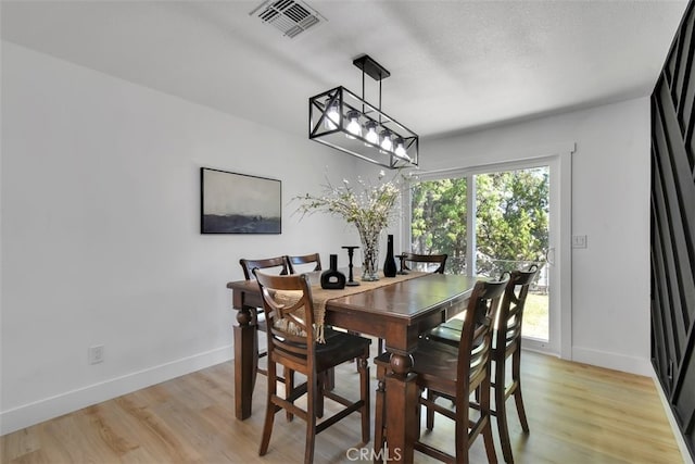 dining room with a wealth of natural light, a textured ceiling, and light wood-type flooring