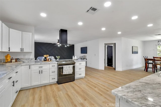 kitchen featuring island range hood, stainless steel range oven, light stone countertops, and white cabinets