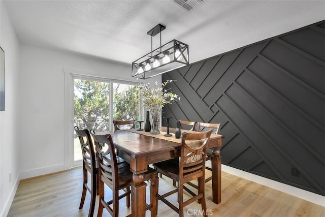 dining room with light hardwood / wood-style floors and a textured ceiling