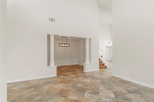 unfurnished living room featuring decorative columns and a high ceiling