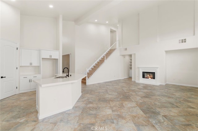 unfurnished living room featuring beamed ceiling, sink, and a high ceiling