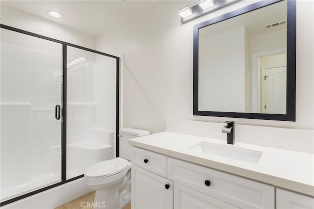 bathroom featuring vanity, a shower with door, and toilet